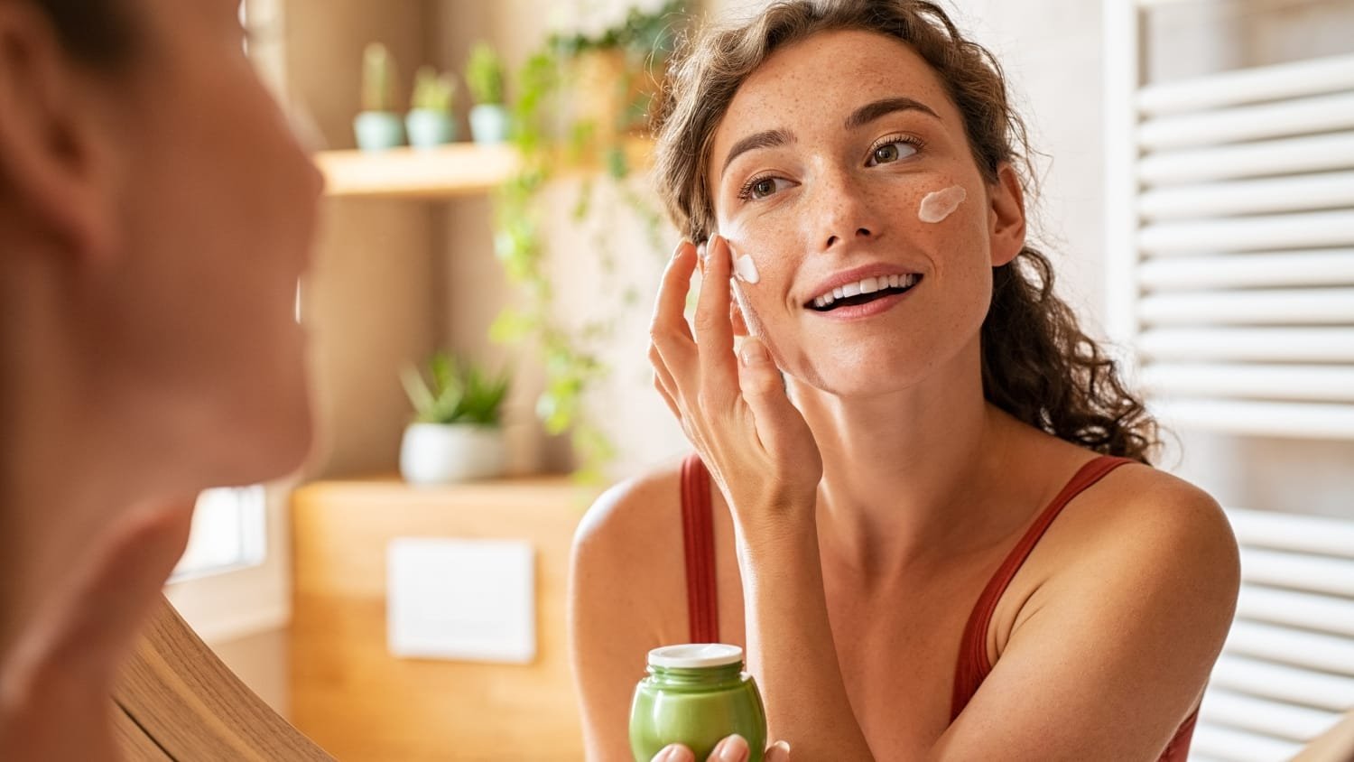 Woman applying moisturizer as part of her daily skincare routine